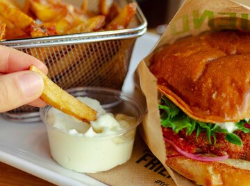 Eine Portion Pommes mit einem Burger und Mayonnaise | © unsplash/K8