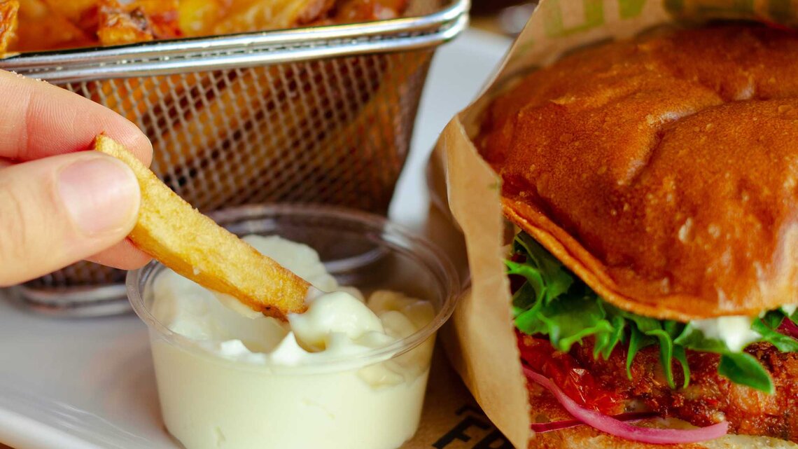 Eine Portion Pommes mit einem Burger und Mayonnaise | © unsplash/K8