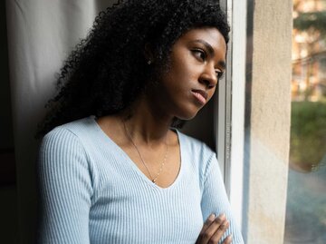 Frau lehnt Kopf an Fenster und schaut deprimiert | © Getty Images/Paolo Cordoni
