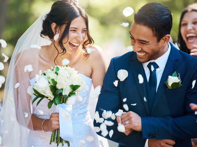 Frisch vermähltes Brautpaar wird mit Rosenblüten beworfen | © Getty Images/PeopleImages