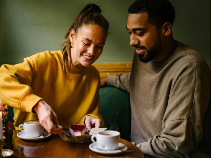 Junges Paar sitzt zusammen im Cafe mit Kuchen  | © Getty Images/Janina Steinmetz