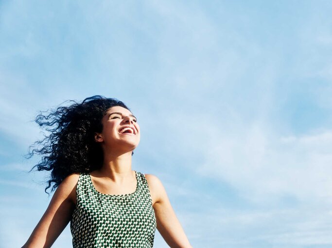 Frau lächelt mit Himmel im Hintergrund | © Getty Images/Tim Robberts