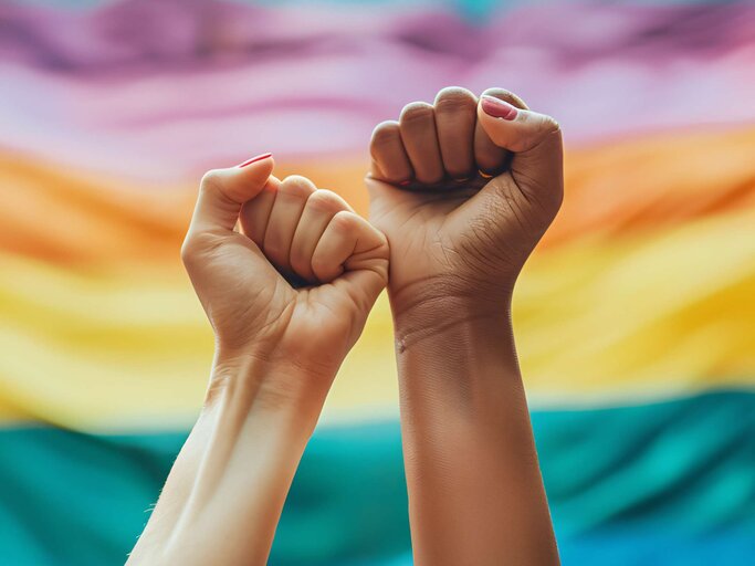 Zwei Fäuste vor einen Pride Flagge | © Adobe Stock/Jess rodriguez/KI