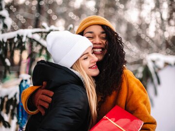 Zwei Freundinnen umarmen sich wegen einem Weihnachtsgeschenk. | © Getty Images/Cavan Images