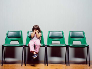 Kind sitzt traurig alleine auf Stühlen. | © Getty Images/Peter Dazeley