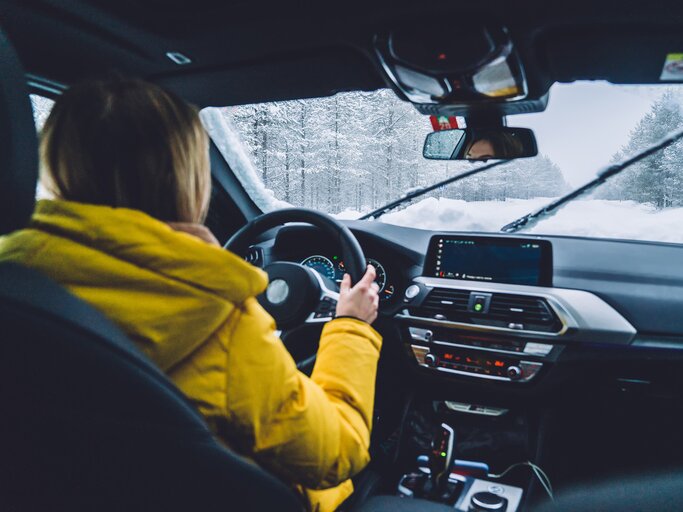 Eine junge Frau trägt eine Winterjacke beim Autofahren. | © Adobestock/BullRun