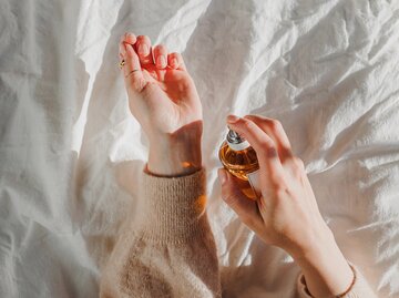 Frau sprüht sich Parfum auf ihren Handrücken | © GettyImages/	Chiociolla