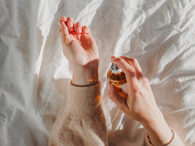 Frau sprüht sich Parfum auf ihren Handrücken | © GettyImages/	Chiociolla