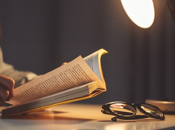 Nahaufnahme von Buch, Brille, Lampe | © Adobe Stock/Goffkein