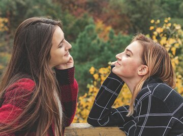 Zwei Frauen sitzen sich gegenüber und lächeln sich an | © AdobeStock/Victoria Kondysenko