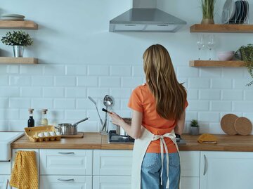 Frau steht mit dem Rücken zur Kamera in der Küche und kocht am Herd. | © Adobe Stock/gstockstudio