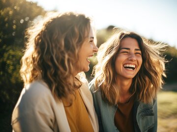  Zwei blonde junge Frauen lachen und haben gemeinsam Spaß in der Natur | © Adobe Stock/Axel Bueckert/Generiert mit KI