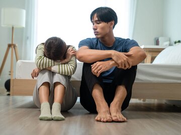 Zwei Personen sitzen nebeneinander auf Boden | © Getty Images/Visoot Uthairam