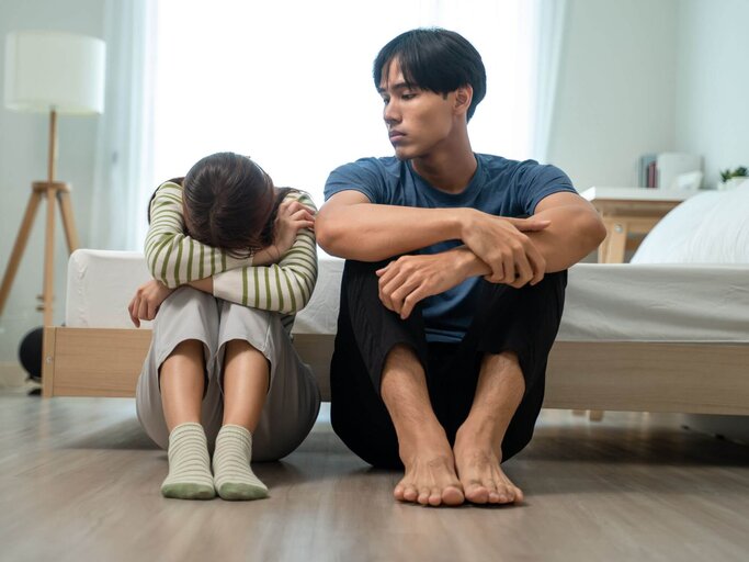 Zwei Personen sitzen nebeneinander auf Boden | © Getty Images/Visoot Uthairam