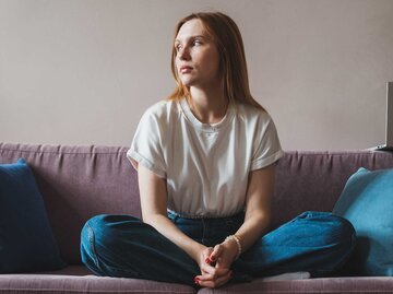 Frau sitzt enttäuscht auf dem Sofa. | © Getty Images/MementoJpeg