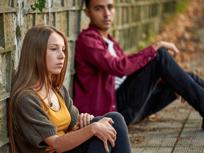 Frau und Mann sitzen traurig am Boden | © Getty Images/LEREXIS