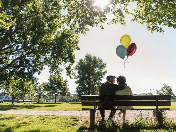 Altes Ehepaar sitzt verliebt auf Parkbank | © Getty Images