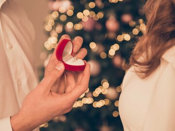 Nahaufnahme Heiratsantrag vor Weihnachtsbaum | © Adobe Stock/deagreez