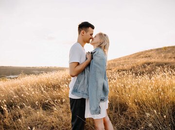 Paar steht auf einem Feld und küsst sich verliebt. | © Adobe Stock/Bostan Natalia