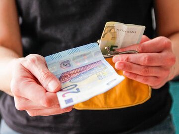 Person mit Geld und Geldbeutel in den Händen | © Getty Images/Kinga Krzeminska