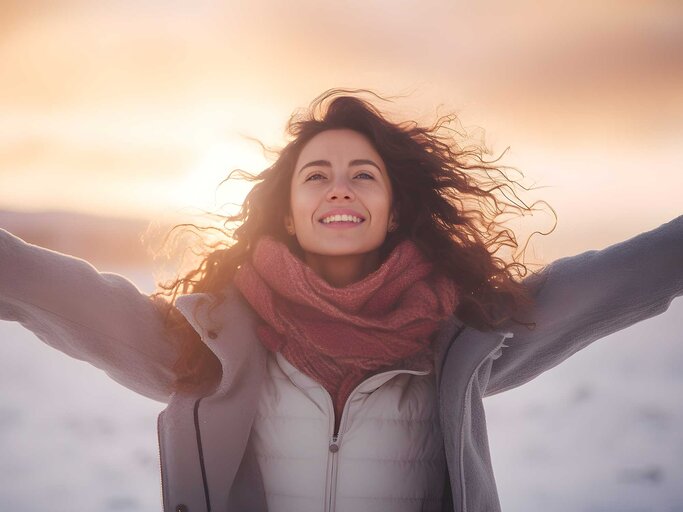 Frau mit offenen Armen in der Wintersonne | © AdobeStock/Jens/Mit KI generiert