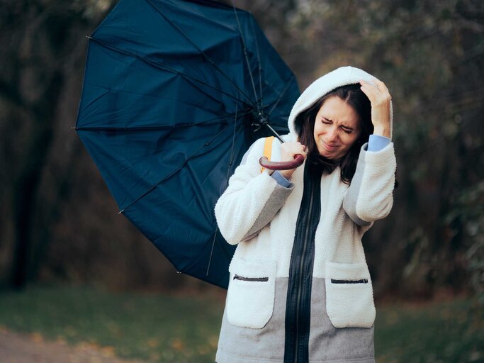 Frau mit umgedrehtem Regenschirm im Regen | © Adobe Stock/nicoletaionescu