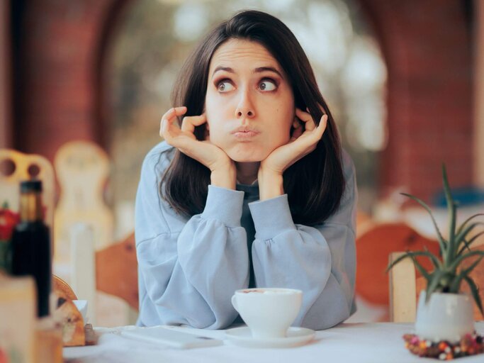 Person sitzt an Tisch und hält sich Ohren zu. | © Getty Images/nicoletaionescu