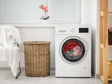 Waschmaschine, neben der ein Wäschepuff steht | © Adobe Stock/Africa Studio