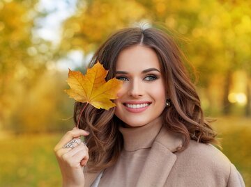 Junge Frau hält Herbstblatt in der Hand | © AdobeStock/millaf