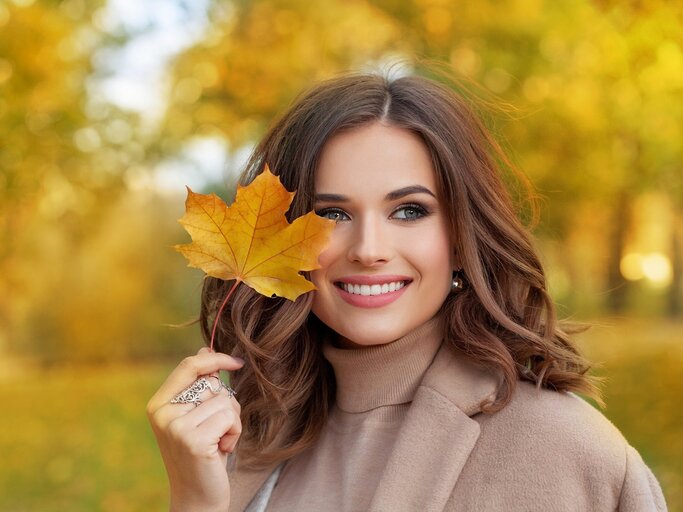 Junge Frau hält Herbstblatt in der Hand | © AdobeStock/millaf