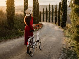 Frau mit Kleid schiebt Fahrrad | © Getty Images/SimonSkafar