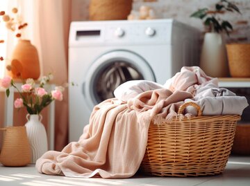 Gefüllter Wäschekorb steht vor der Waschmaschine | © Adobe Stock/meow