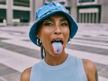 Frau streckt blaue Zunge raus | © Getty Images/Delmaine Donson