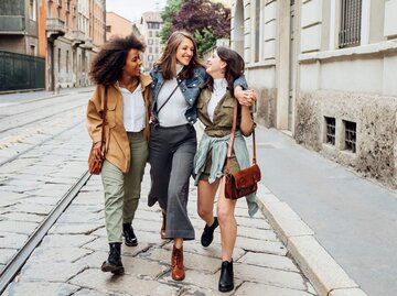 Drei Personen laufen umarmt auf Straße | © Getty Images/Westend61