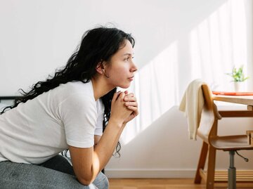 Junge Frau schaut nachdenklich aus dem Fenster | © Getty Images/Xavier Lorenzo