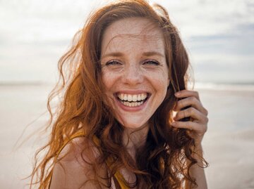 Glückliche junge Frau am Strand | © Getty Images/Westend61