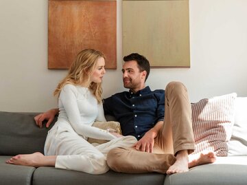 Paar sitzt auf einem Sofa und lächelt sich an | © Getty Images/Lilly Bloom