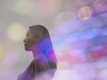 Junge Frau steht in Lichtermeer | © GettyImages/	Jasper James