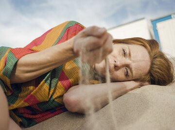 Depressive Frau liegt lustlos im Sand | © GettyImages/Westend61