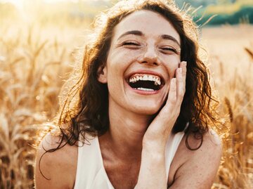 Lächelnde Frau auf einem Weizenfeld | © Adobe Stock/Davide Angelini