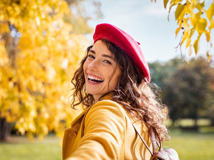 Glückliche Frau mit Baskenmütze in Herbstlandschaft | © AdobeStockRido