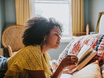 Person liegt in Bett beim Lesen | © Getty Images/Catherine Falls Commercial