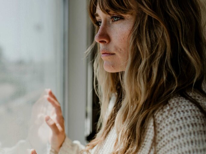 Traurige Frau am Fenster | © Adobe Stock/rawpixel.com