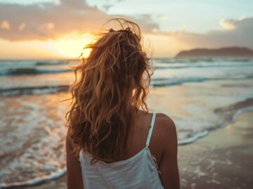 Aufnahme einer Frau am Strand mit welligen Haaren | © Adobe Stock/ChaoticMind