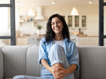 Lächelnde Frau sitzt auf dem Sofa | © Adobe Stock/Prostock-studio