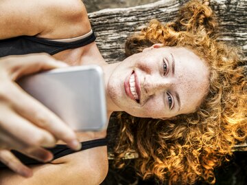 Sympathische junge Frau lächelt und macht ein Selfie mit ihrem Handy | © GettyImages/Westend61