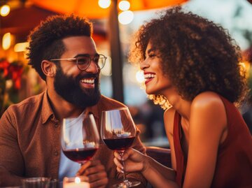 Frau und Mann lachen und trinken Rotwein | © AdobeStock/VisualProduction/Mit KI generiert