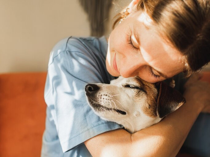 Lächelnde Frau umarmt einen Hund | © GettyImages/Anastasiia Krivenok