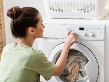 Junge Frau stellt Temperatur bei Waschmaschine ein | © Getty Images/Lightfield Studios