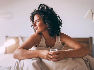 Person im Bett mit Tasse | © Getty Images/FreshSplash